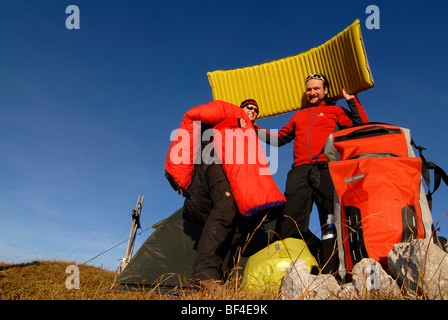 Wanderer, junger Mann und Frau, die Spaß beim Aufstellen von einem Biwak mit Rucksack, Zelt, Schlafsack und Isomatte, Heidachst Stockfoto