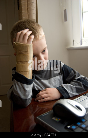 Junge mit Arm in Schiene mit einem laptop Stockfoto