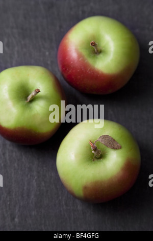 Grüne und rote Holzäpfel auf einer Schiefertafel Tafel. Stockfoto