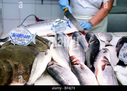 Fischhändler schneidet Lachs hinter Steinbutt (links) und Bass zum Verkauf an Fisch stall auf dem zentralen Markt Mercado Central Valencia Stockfoto