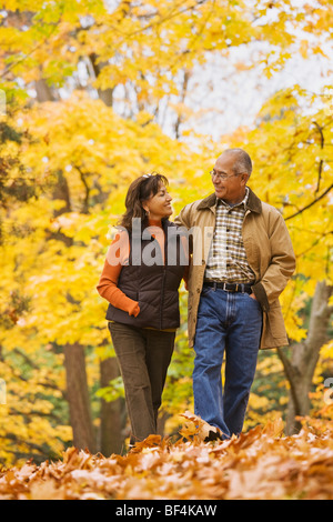 Hispanische Paare, die im Herbstlaub Stockfoto