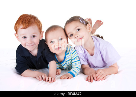 Drei Kinder auf weißen Bett mit isolierten Hintergrund Stockfoto