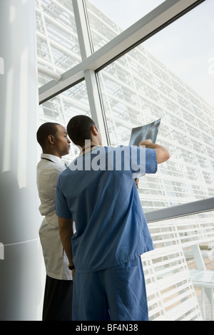 Multi-ethnischen Arzt und Krankenschwester Überprüfung Röntgen durch Fenster Stockfoto