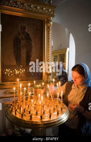 Frau entzünden Altarkerzen in der orthodoxen Kirche, Jekaterinburg, Russland Stockfoto