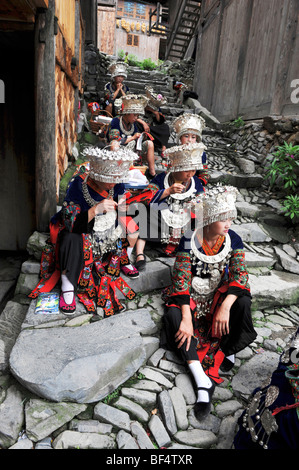 Miao junge Frauen sitzen auf gepflasterten Treppen, Xijiang Miao Dorf, Leishan Grafschaft, Stadt Kaili, Guizhou Provinz, China Stockfoto
