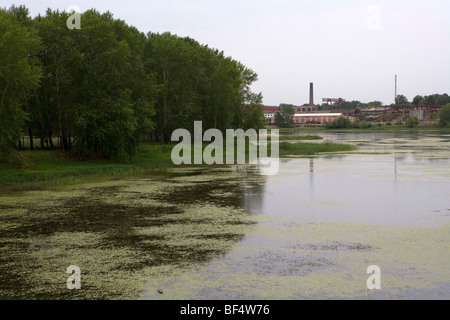 Verschmutzter Fluss mit Algen Wachstum und industrielle Gebäude im Hintergrund, Ural, Russland Stockfoto