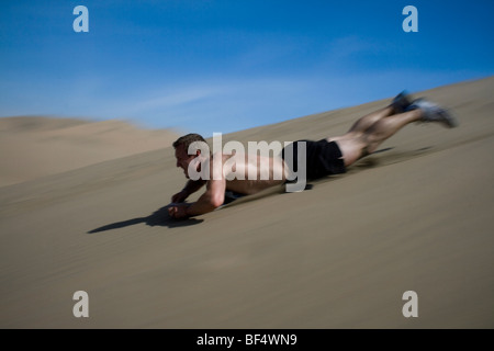 Ein sandboarder fliegt eine Sanddüne in der Wüste Oase von Huacachina, Ica, Peru, Südamerika Stockfoto