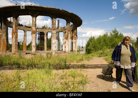 Frau mit Einkaufswagen auf Feldweg durch Rundschreiben verlassenen Industriegebäude, Tagil, Ural, Russland Stockfoto