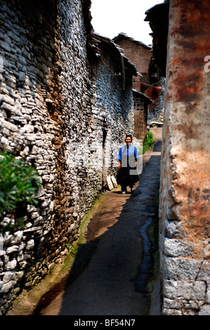 Eine Seniorin Dong zu Fuß in einer engen Gasse Qiandongnan der Miao und Dong autonomen Präfektur, Provinz Guizhou, China Stockfoto