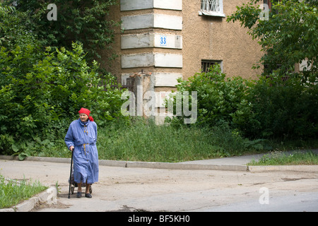 Ältere Frau mit Einkaufswagen auf der Straße außerhalb des sozialen Wohnungsbaus apartment, Jekaterinburg, Ural, Russland Stockfoto