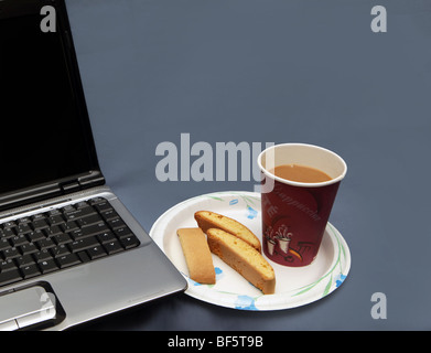 Frühstück auf dem Laptop. Kaffee und Gebäck am Computer. Stockfoto