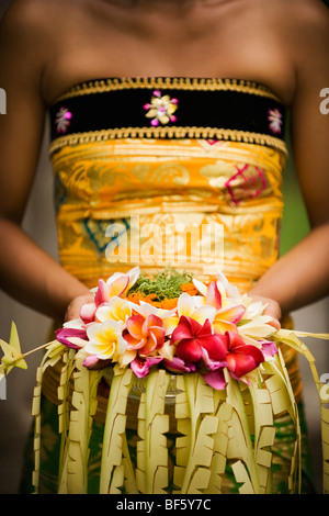 Eine Nahaufnahme der balinesischen Frau hält ein Blumenarrangement. Stockfoto
