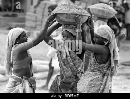 Indische Frauen arbeiten auf den Straßen, Heben und Tragen Sand in eine Schüssel auf dem Kopf. Puttaparthi, Andhra Pradesh, Indien. Schwarzweiß Stockfoto