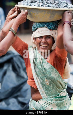 Indische Frau arbeiten auf den Straßen, Steine in einer Schüssel auf dem Kopf. Puttaparthi, Andhra Pradesh, Indien Stockfoto