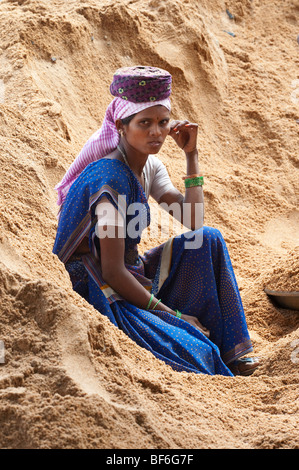 Indische Frau in einen Haufen Sand ausruhen, während auf den Straßen in Puttaparthi, Andhra Pradesh, Indien, sitzen Stockfoto