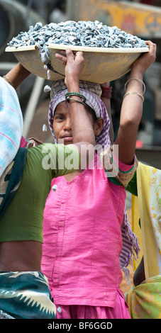 Junge indische Frau arbeiten auf den Straßen Steine in einer Schüssel auf dem Kopf. Puttaparthi, Andhra Pradesh, Indien Stockfoto