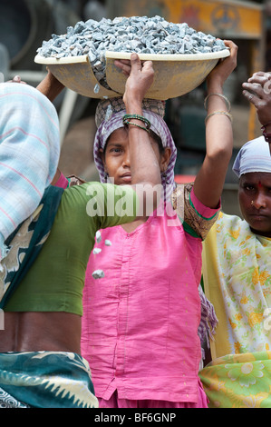 Junge indische Frau arbeiten auf den Straßen Steine in einer Schüssel auf dem Kopf. Puttaparthi, Andhra Pradesh, Indien Stockfoto