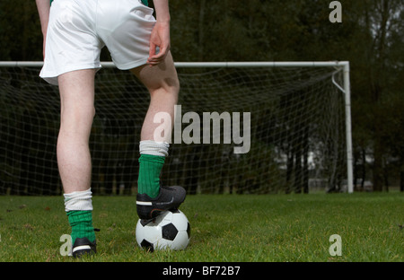 Fußballspieler mit Fuß auf den ball auf die Strafe vor Ort mit Blick auf eine leere Tor stehend Stockfoto