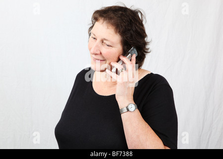 Reifen der 50er Jahre 60er Jahre späten Mittleren Alter Frau im Gespräch im Chat auf Handy zellulären mit grauen moderne Technologie-Generation Stockfoto