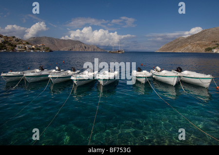 Eine Reihe von acht kleine Boote vor Anker im Hafen von Symi-Stadt, Griechenland. Stockfoto