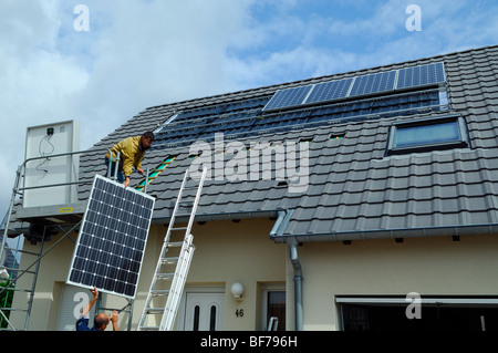 Arbeiter, die Installation von Photovoltaik-Solarzellen auf dem Dach eines Privathauses Stockfoto