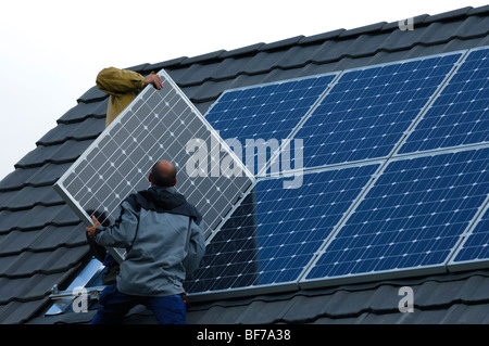 Arbeiter, die Installation von Photovoltaik-Solarzellen auf dem Dach eines Privathauses Stockfoto