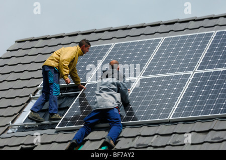 Arbeiter, die Installation von Photovoltaik-Solarzellen auf dem Dach eines Privathauses Stockfoto