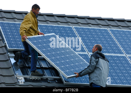 Arbeiter, die Installation von Photovoltaik-Solarzellen auf dem Dach eines Privathauses Stockfoto