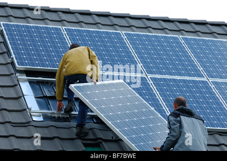 Arbeiter, die Installation von Photovoltaik-Solarzellen auf dem Dach eines Privathauses Stockfoto