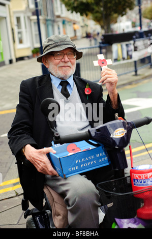 Jährlicher Tag der Mohn Appell: älteren Mann im Rollstuhl Verkauf Erinnerung Mohn in der Straße Wales UK deaktiviert Stockfoto