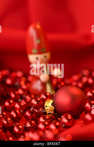 Rote Christbaumkugel mit Holzfigur im Hintergrund Stockfoto