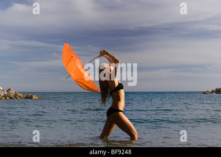 Frau im Meer mit orange Dach gegen stürmischen Himmel Stockfoto