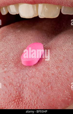 Eine hellere rosa Pille sitzt auf einem menschlichen weiblichen Zunge Stockfoto