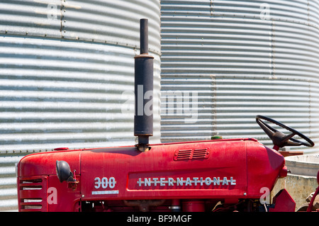 roter Traktor in von Getreidesilos Stockfoto