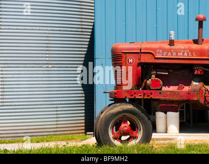 roter Traktor in von Getreidesilos Stockfoto