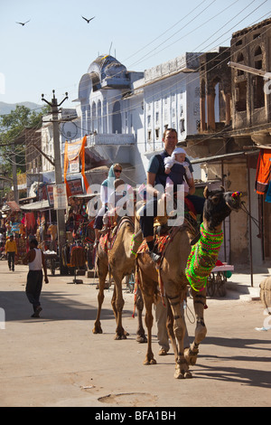 Touristen, die während der Camel Fair in Pushkar Indien Kamele reiten Stockfoto