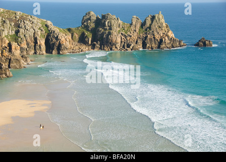 Logan Rock, zwei Surfer kommen aus Wasser, Porthcurno Strand, Pedn Vounder Beach, South Coast, Cornwall, England, UK Stockfoto