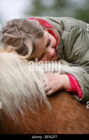 inländische Pferd (Equus Przewalskii F. Caballus), Mädchen sitzen auf einem Pferd, lächelnd und legen ihren Kopf auf seine Mähne, Deutschland Stockfoto