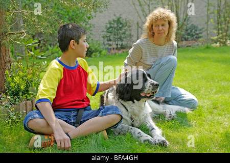 Mutter und Sohn mit ihren Familienhund in ihrem Garten hinter dem Haus Stockfoto