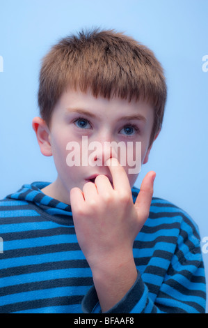 Ein Model Release Bild eines zehn Jahre alten Jungen sammeln seine Nase in seinem Schlafzimmer im Vereinigten Königreich Stockfoto
