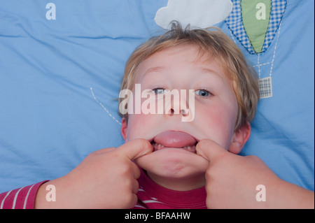 Ein Model Release Bild eines sechsjährigen Jungen ziehen ein dummes Gesicht drinnen im Vereinigten Königreich Stockfoto