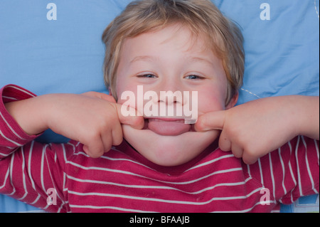 Ein Model Release Bild eines sechsjährigen Jungen ziehen ein dummes Gesicht drinnen im Vereinigten Königreich Stockfoto