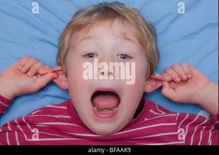 Ein Model Release Bild eines sechsjährigen Jungen ziehen ein dummes Gesicht drinnen im Vereinigten Königreich Stockfoto