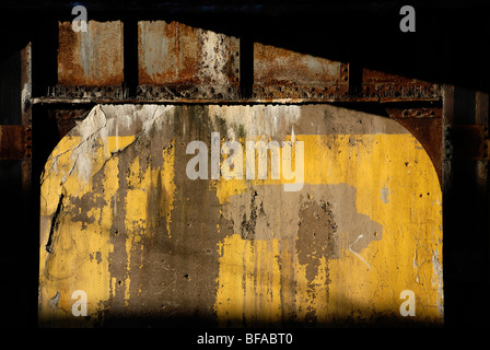 Gelbe Wand unter Eisenbahnviadukt Stockfoto