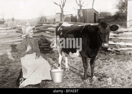 Alte Frau, die darauf warten, Milchkuh auf einem Bauernhof Stockfoto