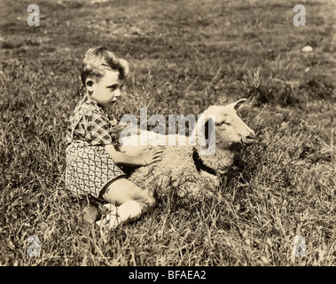 Boy Holding Lamm auf der Weide Stockfoto