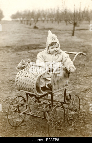 Kleine Mädchen & Teddybär in Wicker Kinderwagen Stockfoto