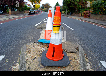 zwei Leitkegel markieren einen beschädigten Abschnitt der Straße in Teddington, Middlesex, england Stockfoto