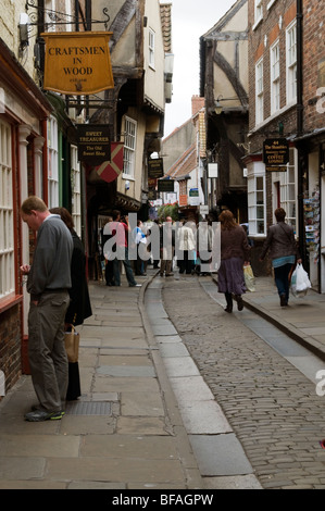 Menschen suchen in Schaufenstern und zu Fuß nach unten einen gepflasterten Gehweg, genannt The Shambles in der historischen Stadt York England Stockfoto