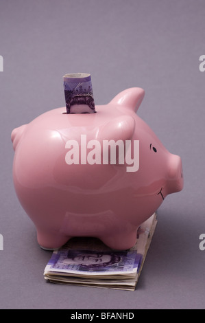 Piggy Bank über einen Stapel von britischen Geld Stockfoto